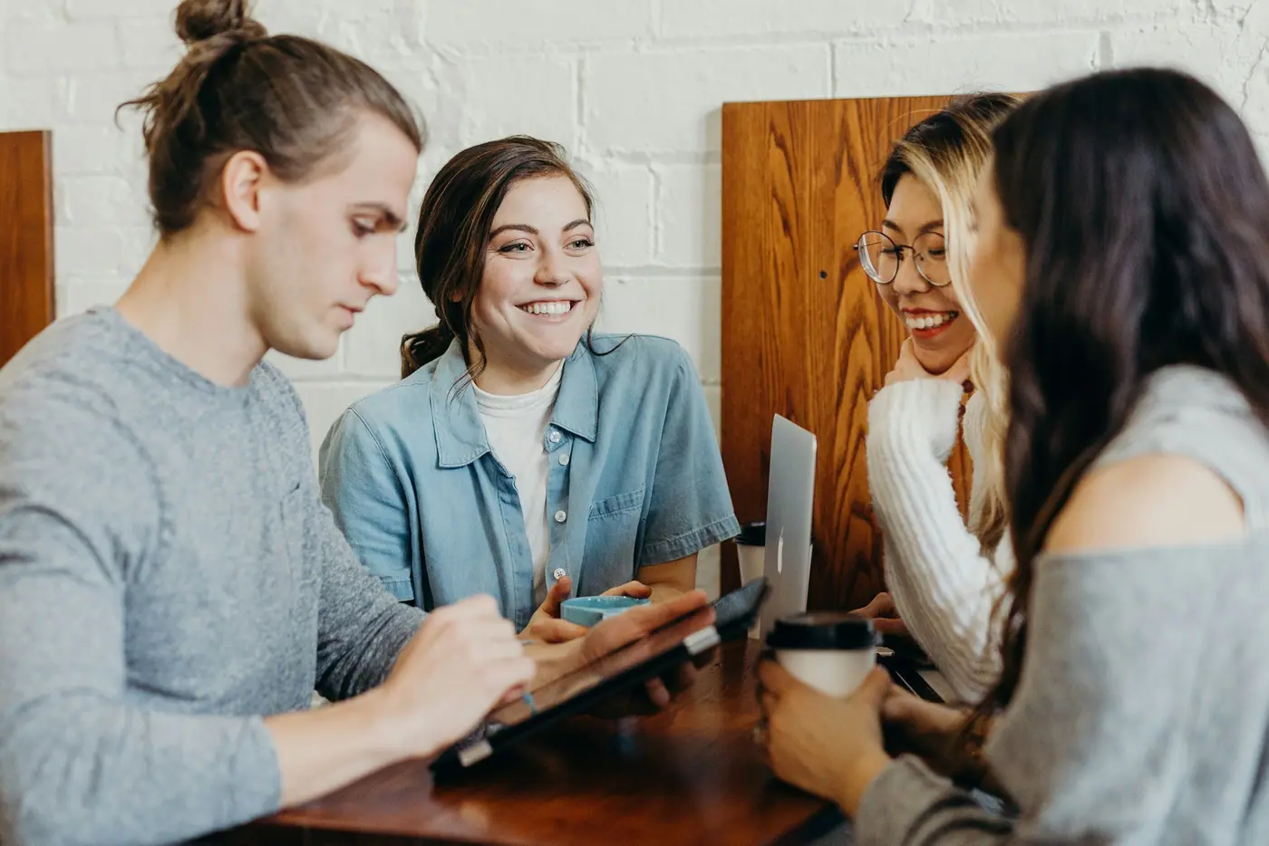 Grupo de jóvenes conversando y mirando sus teléfonos alrededor de una mesa