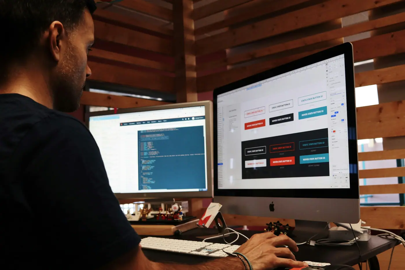 Persona trabajando frente a un monitor con el diseño de un sitio web en una oficina con paredes de madera